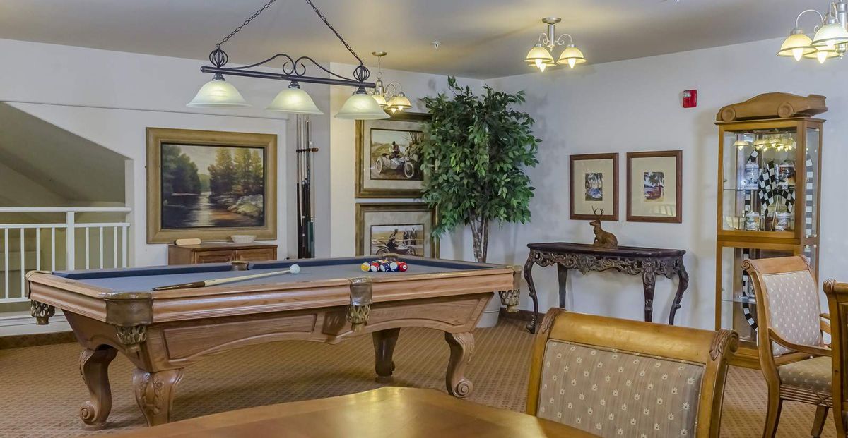 A stylish billiards room with a pool table, comfortable seating, and elegant decor.