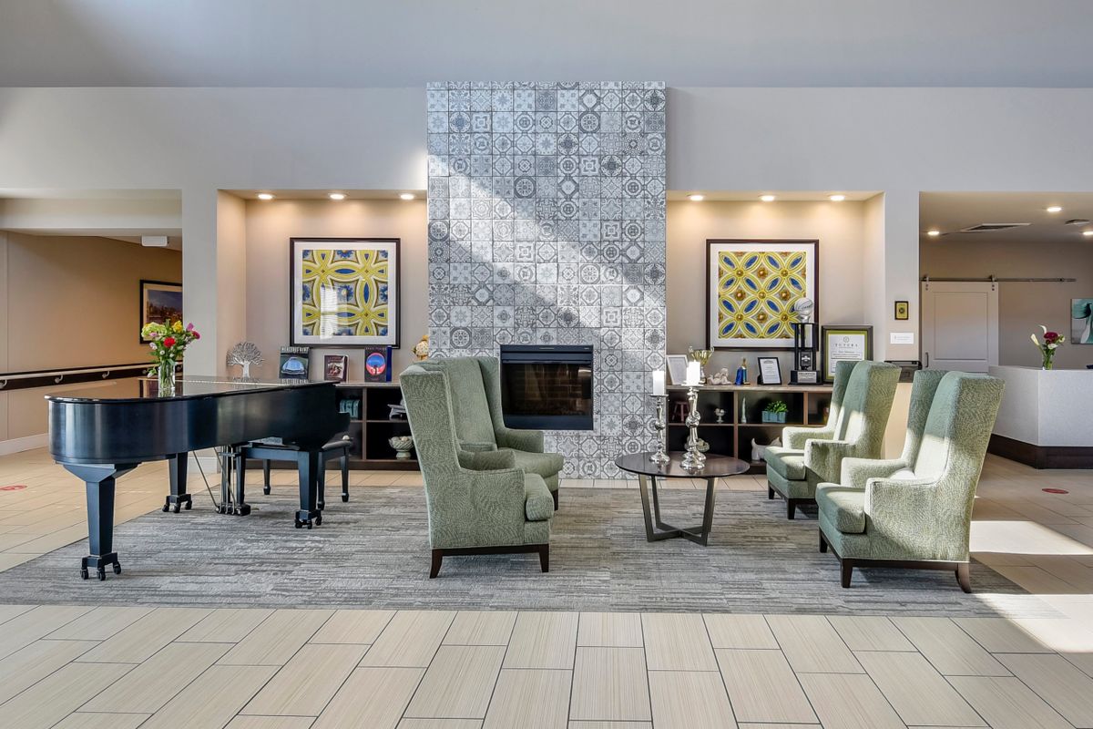 A modern lobby featuring a cozy seating area with a fireplace, piano, and decorative artwork.