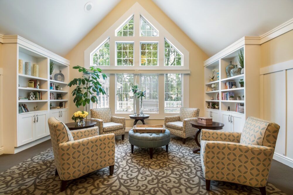 A cozy living room with large windows, bookshelves, and comfortable seating.