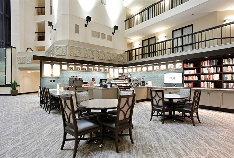 A modern cafe interior with tables and chairs arranged in a spacious seating area.