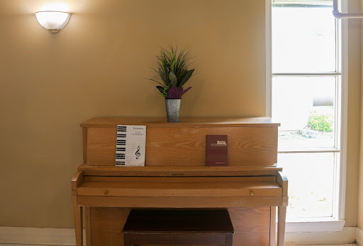 A wooden piano adorned with a decorative plant and sheet music, creating a cozy indoor ambiance.