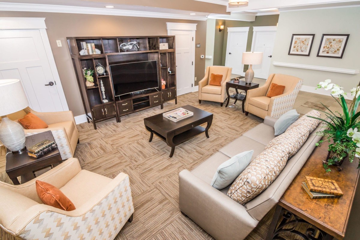 A cozy and well-furnished living room featuring a television, sofa, armchairs, and a coffee table.