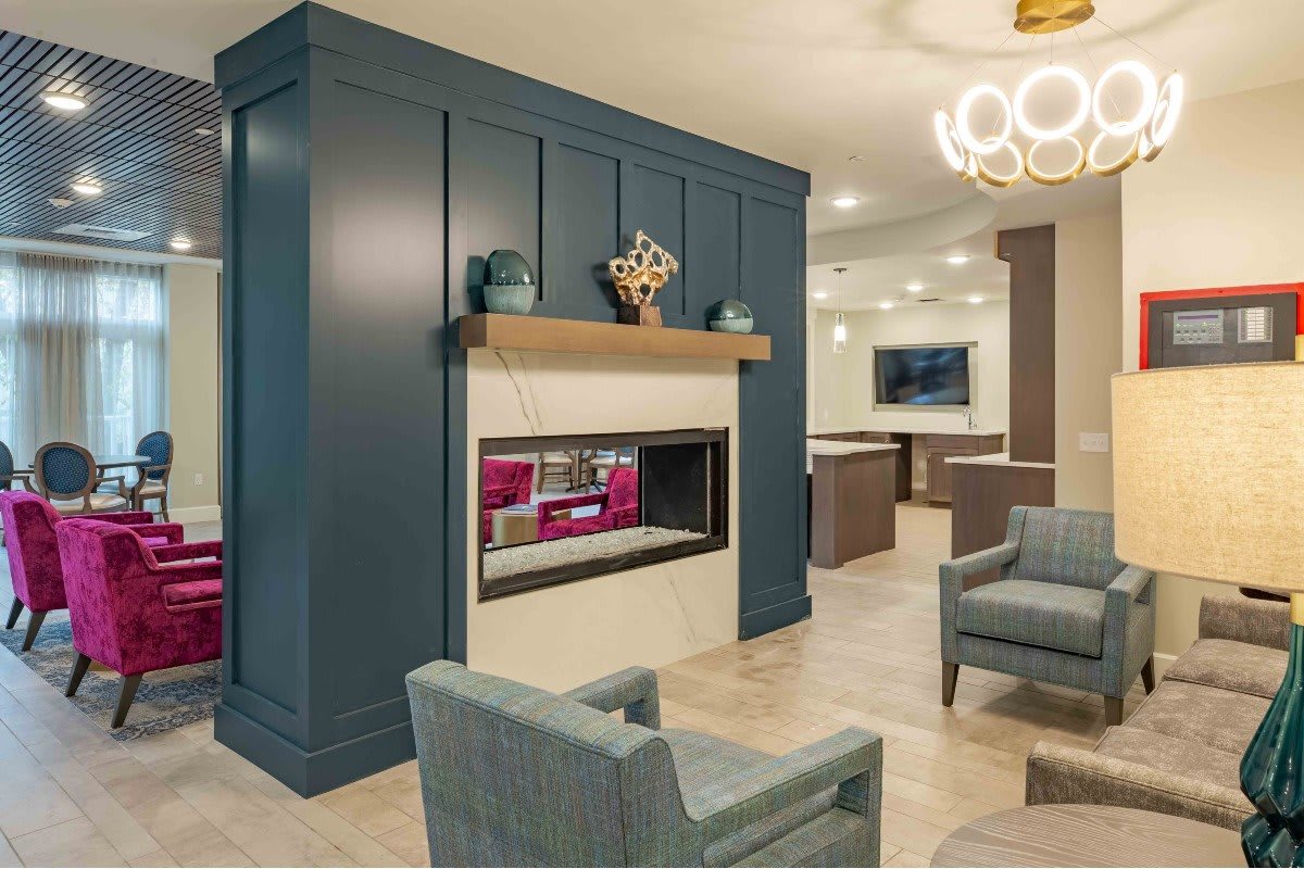 A modern living room with a central fireplace, comfortable armchairs, and elegant decor.