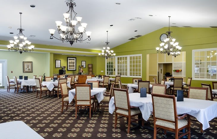 Elegant dining room with neatly arranged tables and chandeliers.