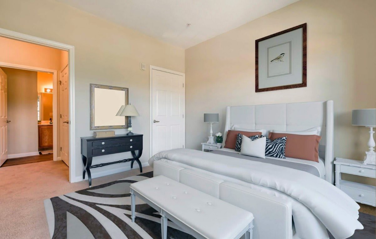 A modern bedroom with stylish decor, featuring a large bed, a dresser with a mirror, and elegant lighting.