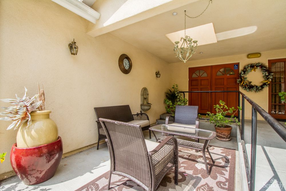 A cozy outdoor patio with rattan furniture and decorative plants.