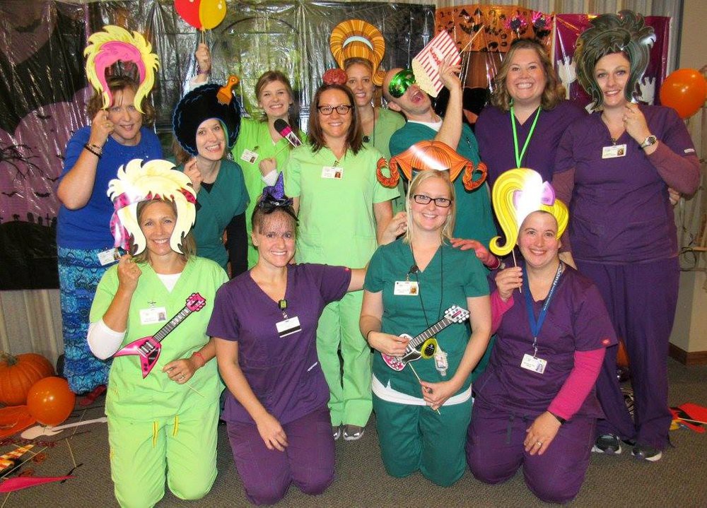 A group of people in uniforms and colorful wigs posing together, smiling and having fun.