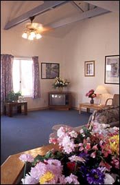 A cozy living room with a sofa, television, and floral decorations.