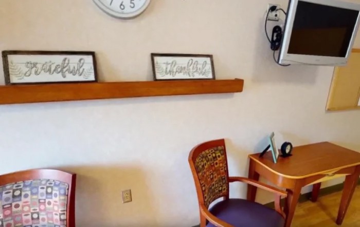 A cozy room with a clock, chairs, and simple decor on the wall.