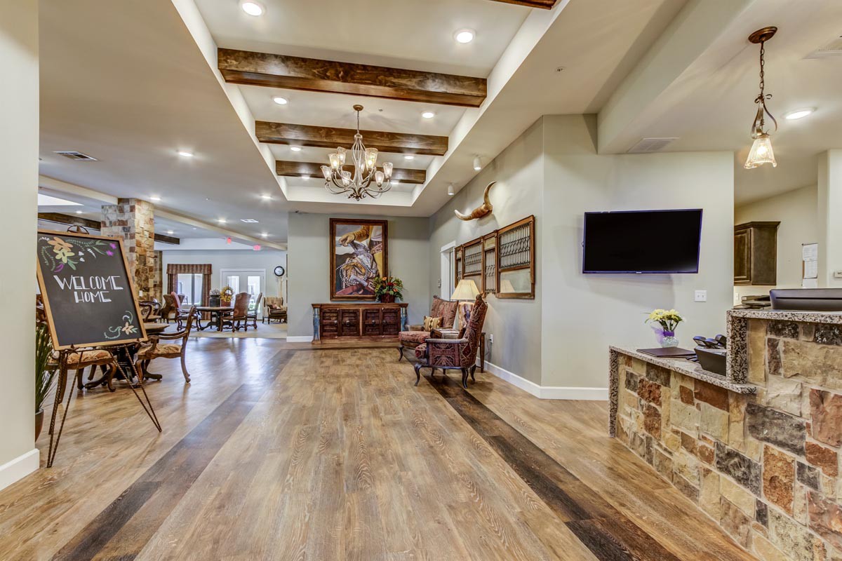 A spacious and elegantly designed lobby featuring wood flooring and a chandelier.