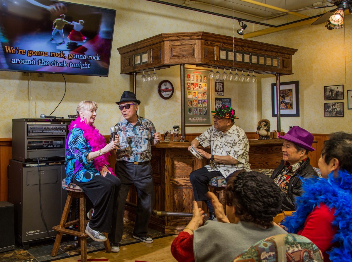A group of seniors enjoys a lively karaoke session in a cozy room.