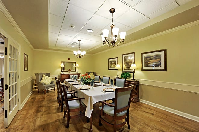 An elegantly set dining room with a long table, surrounded by chairs and decorated with artwork on the walls.