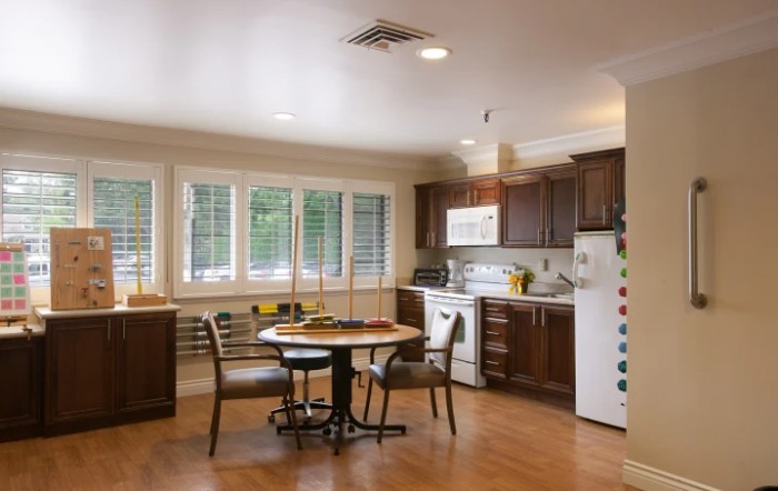 A cozy kitchen with a dining area featuring wooden floors, cabinets, and a round table with chairs.
