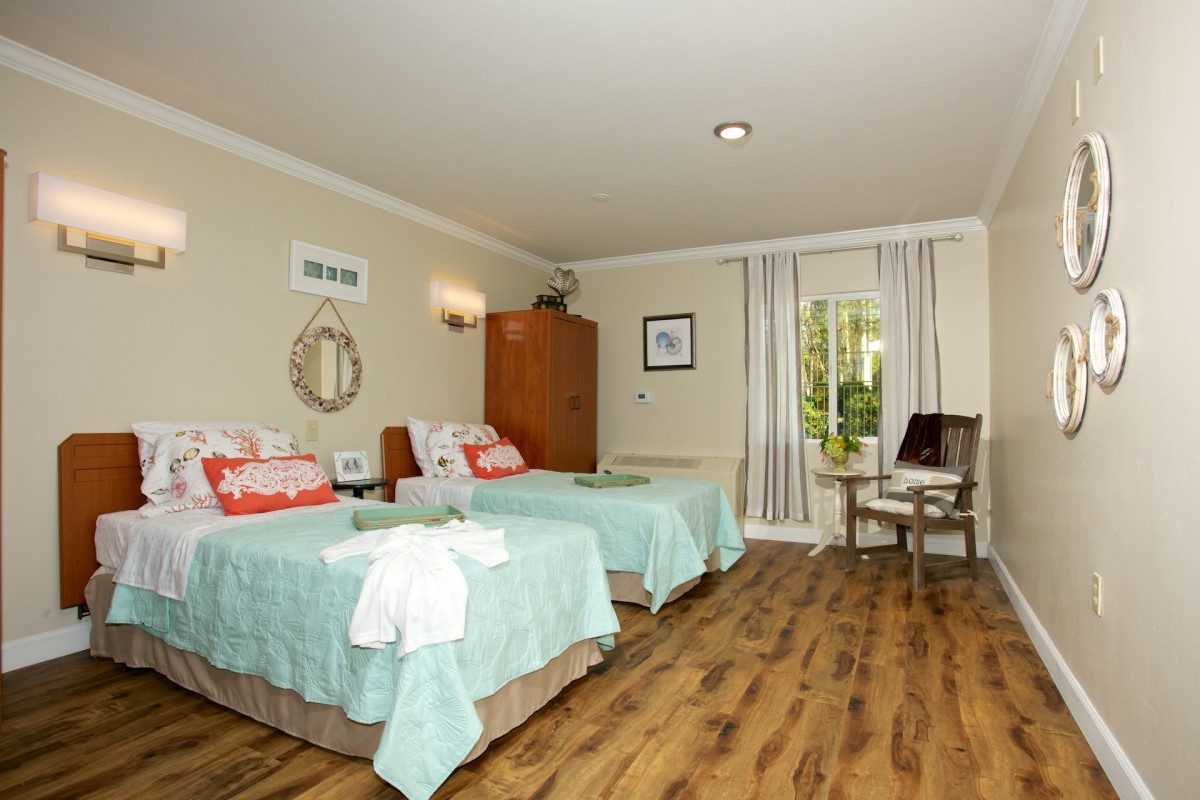 A cozy bedroom with two neatly made beds, decorative pillows, and a wooden floor.