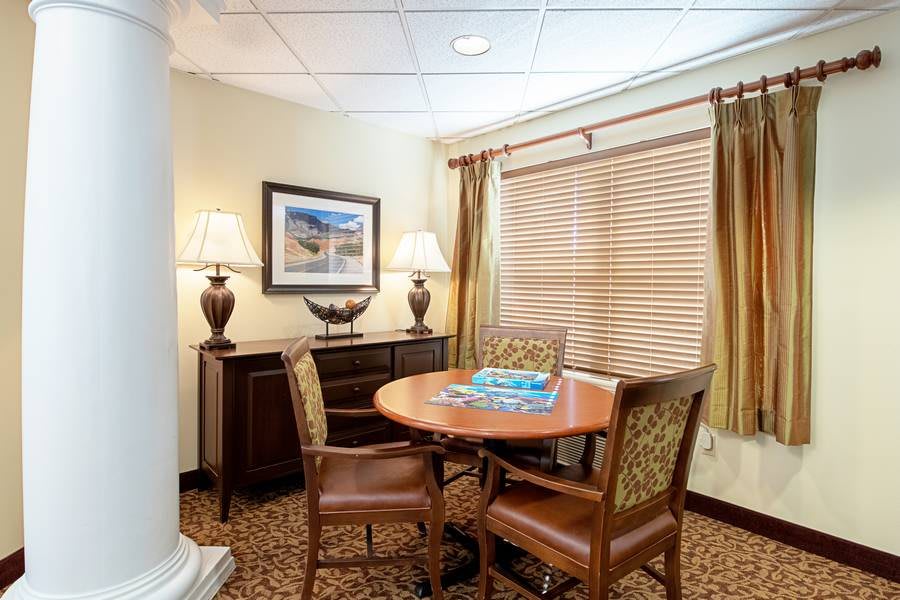 A cozy office space with a round table, chairs, lamps, and decorative elements.