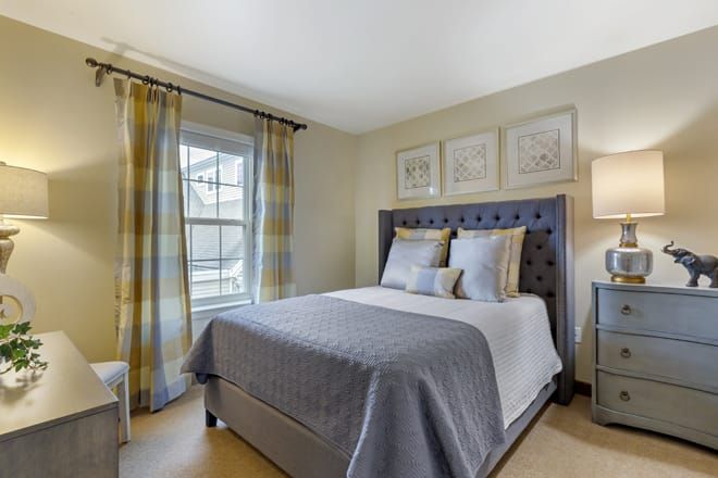 A cozy bedroom with a neatly made bed, elegant curtains, and wall art.