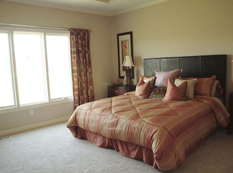 A cozy bedroom with a king-sized bed, pillows, and patterned curtains.