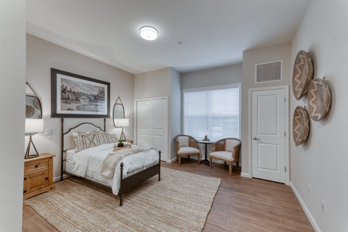 A modern and cozy bedroom featuring a comfortable bed, two chairs by the window, and stylish decor.