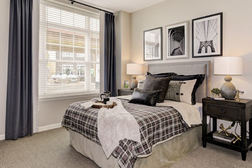 A cozy bedroom featuring stylish decor, complete with a comfy bed, decorative pillows, framed artwork, and a large window allowing natural light.