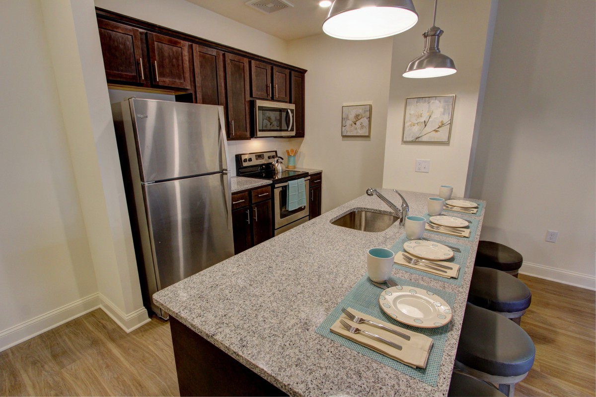 A modern kitchen with stainless steel appliances, granite countertops, and bar seating.