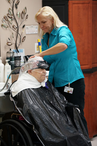A stylist provides a hair treatment to a senior citizen in a salon setting.