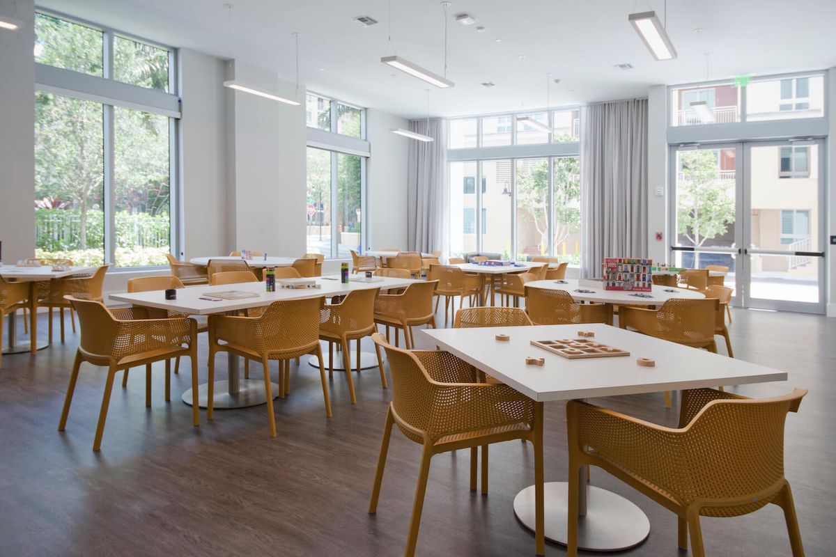 A modern, well-lit room with wooden chairs and tables arranged in a neat format.