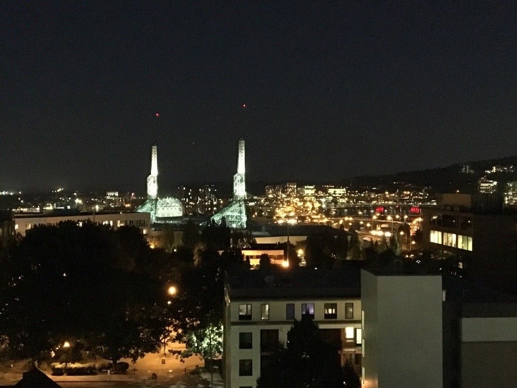 A nighttime cityscape featuring a mosque with illuminated minarets.
