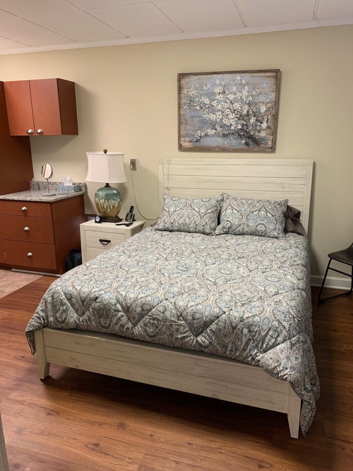 A cozy bedroom with a neatly made bed, nightstand and decorative elements.