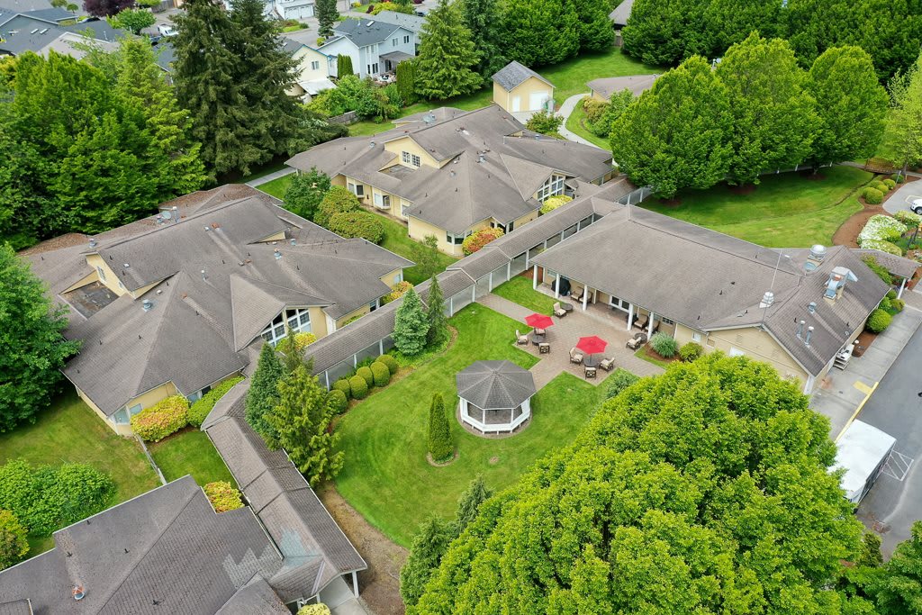 Aerial view of a residential building complex surrounded by greenery, featuring a courtyard with a gazebo and outdoor seating.