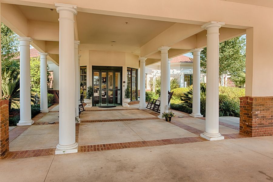 A covered entrance with columns and landscaped surroundings.
