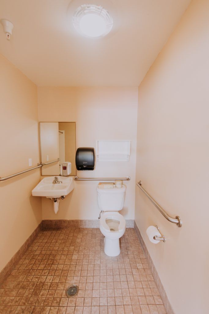 Accessible bathroom with toilet, sink, and handrails.
