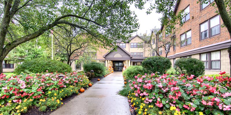 A picturesque garden pathway lined with colorful flowers leads to a charming building.