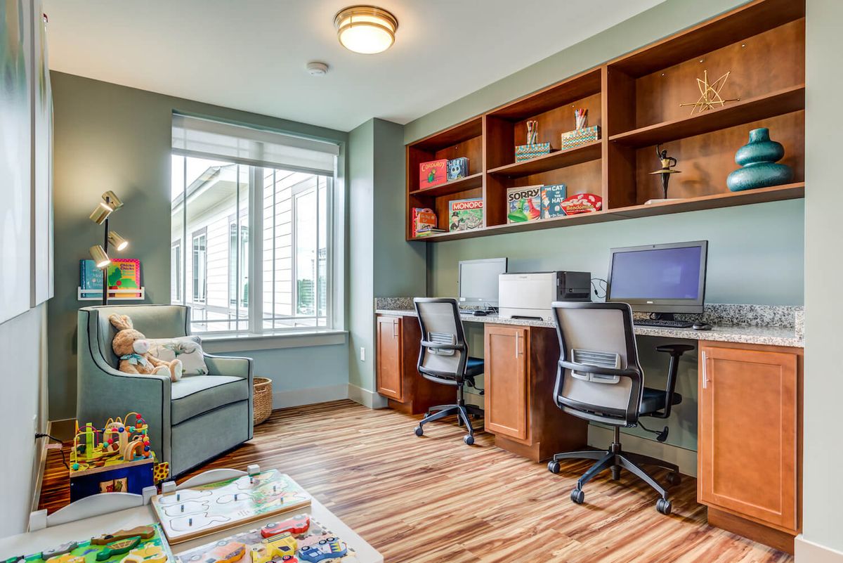 A well-organized home office with dual workstations and ample natural light.