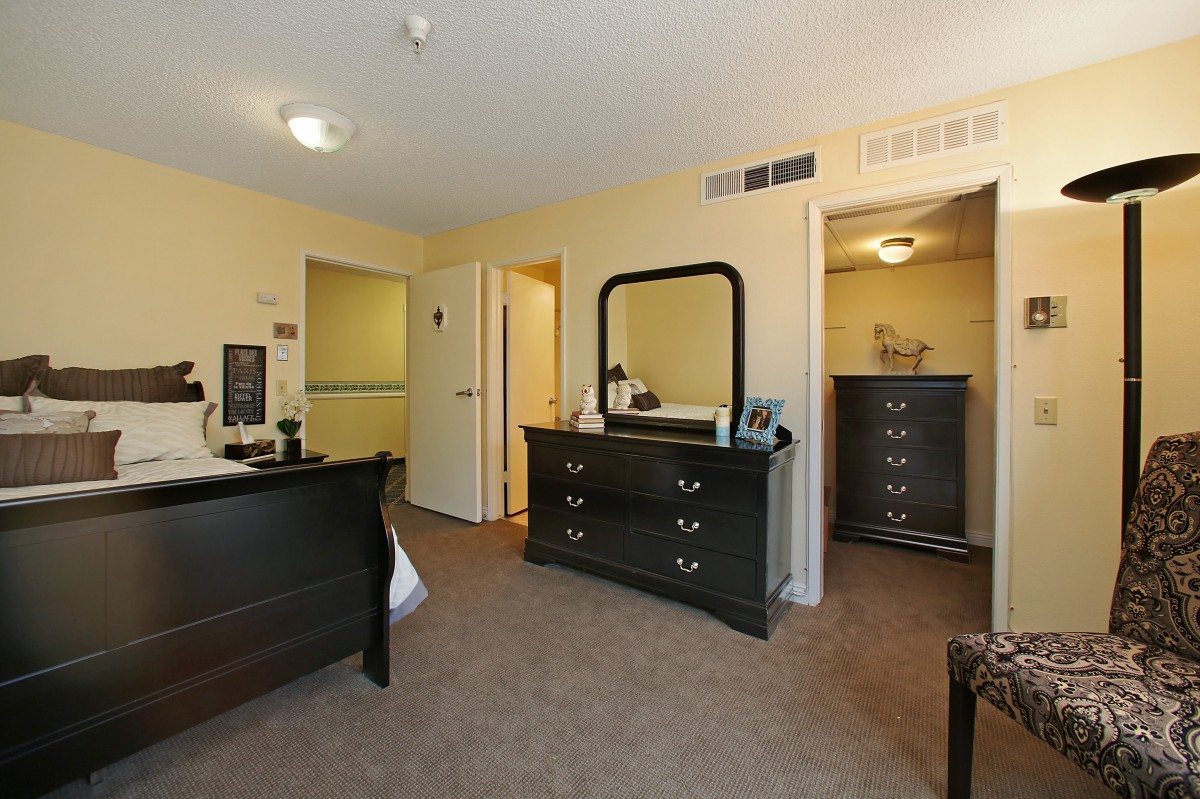 A cozy bedroom with a dresser, mirror, and closet featuring neutral colors.