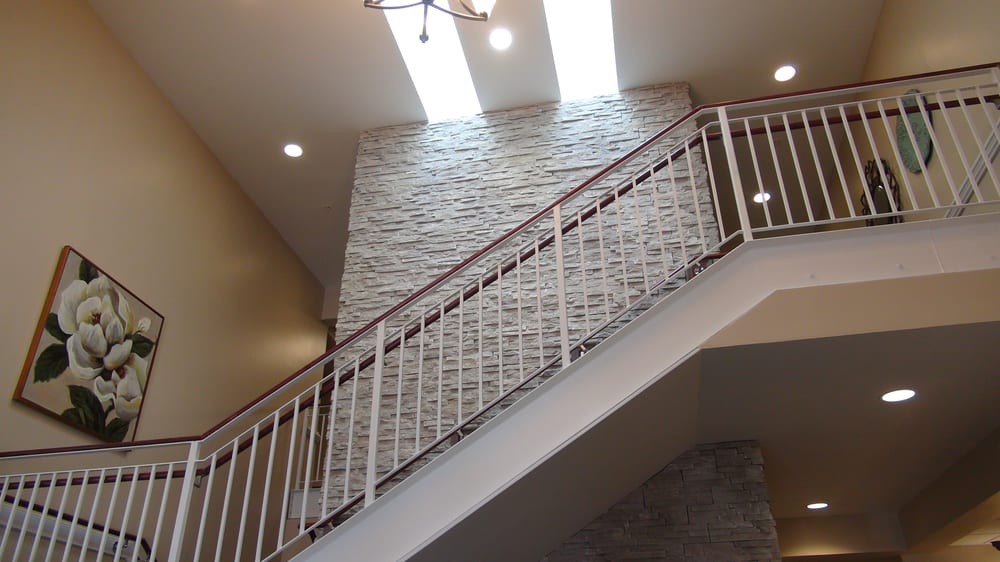 A modern staircase with a textured wall and skylights above.