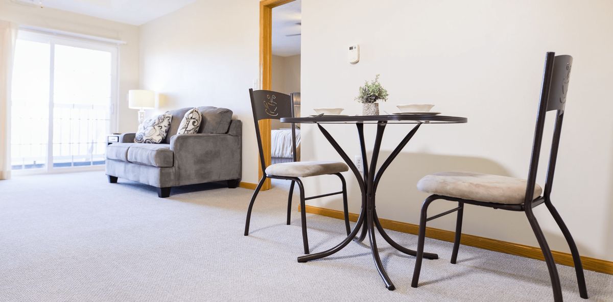 A minimalist living room with a small table and chairs set, alongside a comfortable sofa.