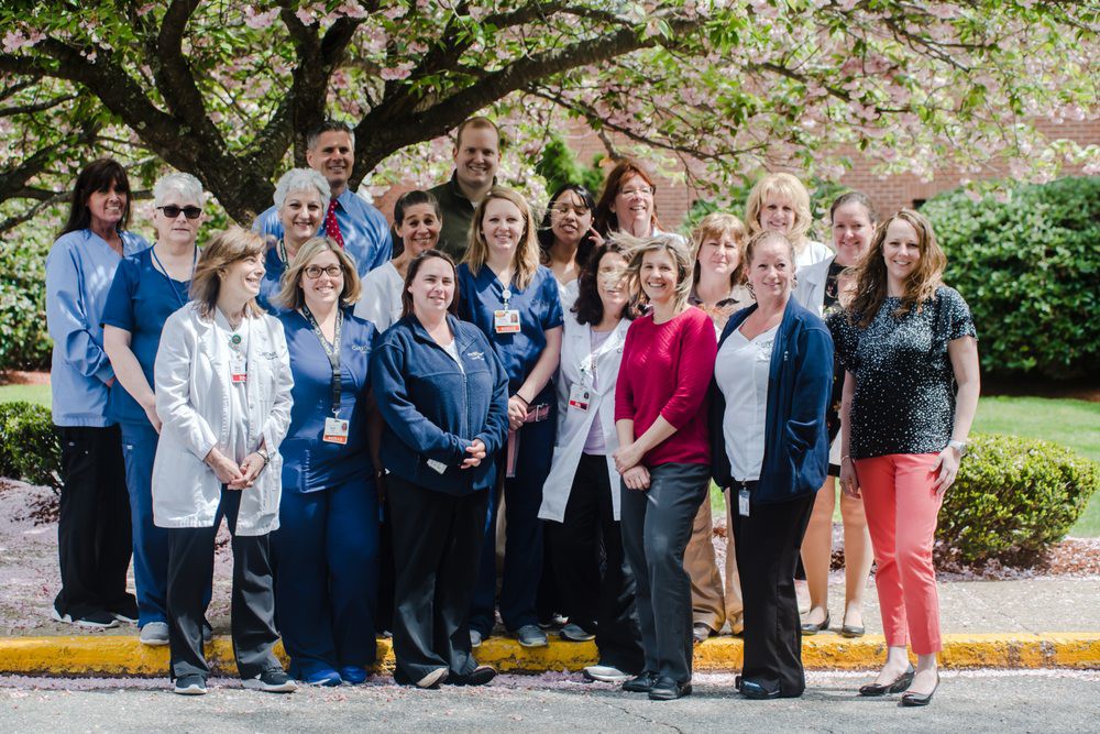 A group of people posing together under a blooming tree on a sunny day.