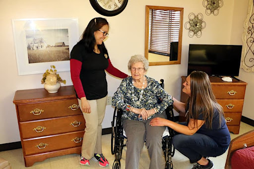A warm moment shared between caregivers and an elderly woman in a comfortable indoor setting.