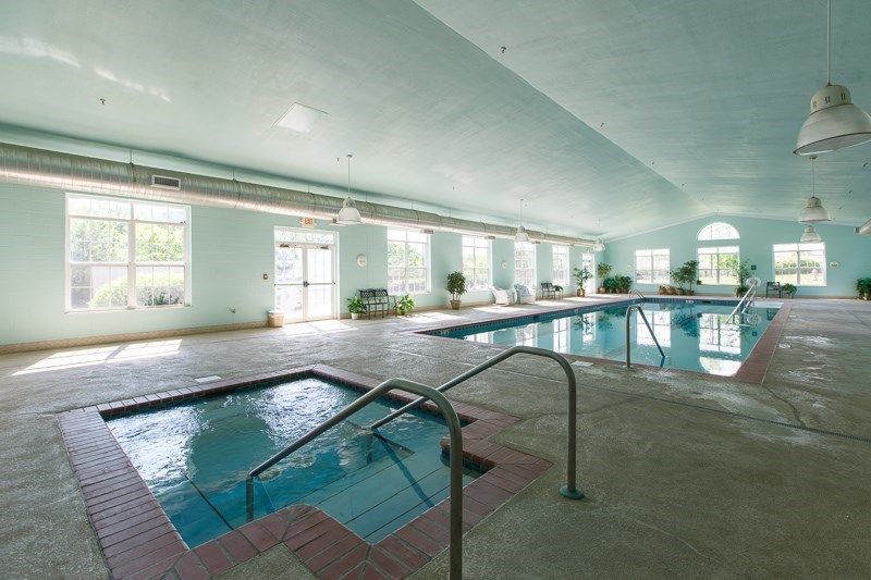An indoor facility featuring a swimming pool and jacuzzi surrounded by large windows.