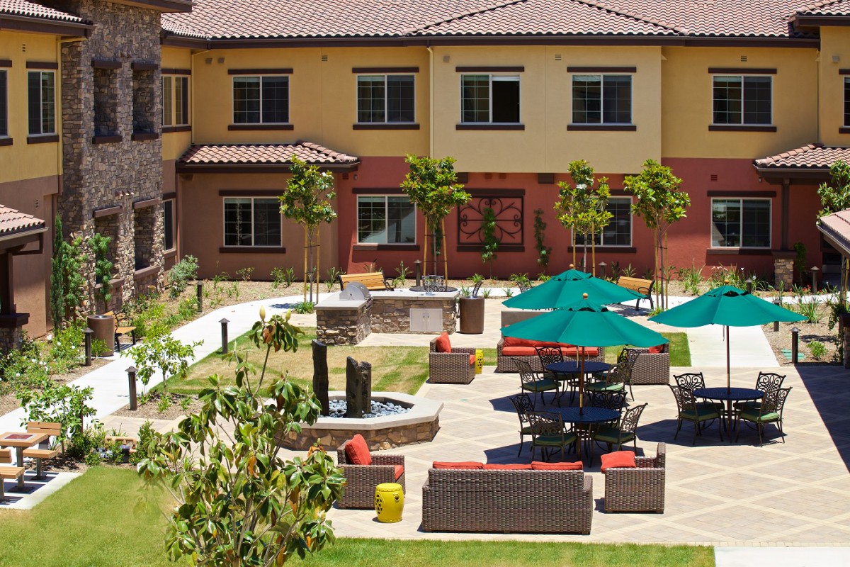 A well-maintained courtyard featuring outdoor seating, umbrellas, and a small fountain.