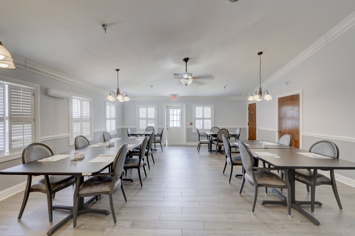 A modern dining area with multiple tables and chairs, well-lit by ceiling lights.
