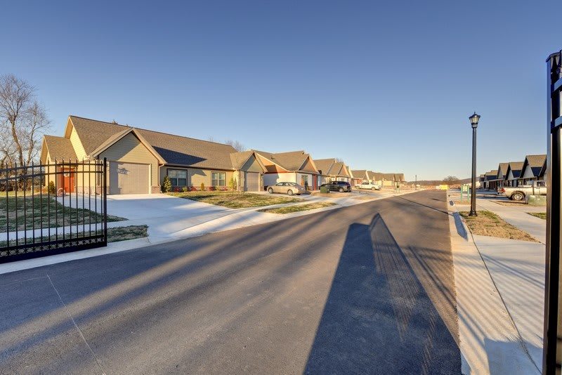 A quiet suburban street lined with residential houses under a clear blue sky.