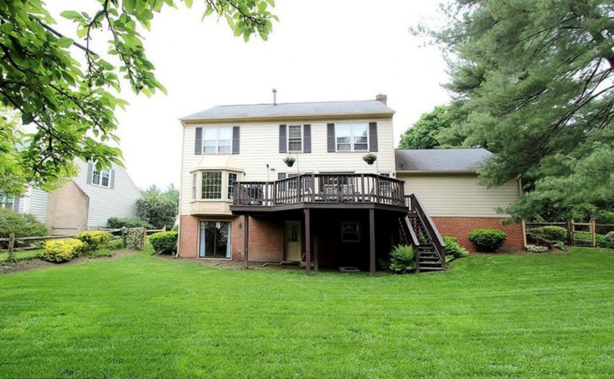 A two-story house with a spacious deck overlooking a green backyard.