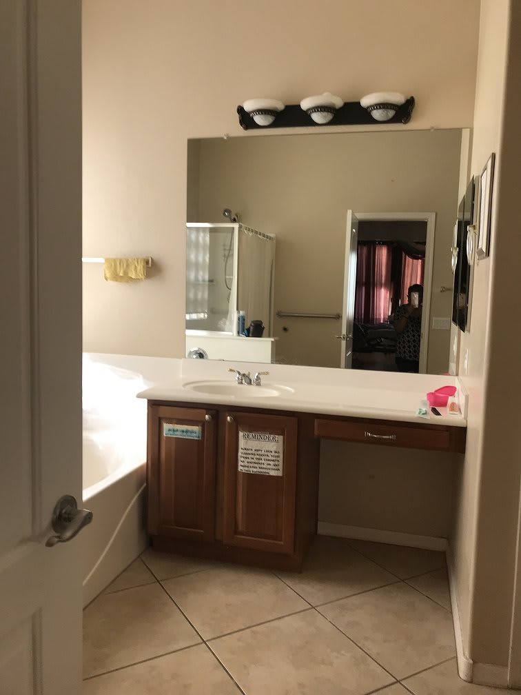 A modern bathroom with a large mirror, single sink vanity, and bathtub.
