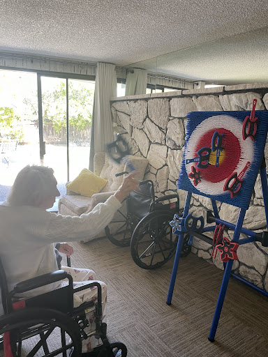An elderly person engaged in a target game activity indoors, promoting rehabilitation and exercise.