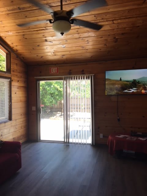 A cozy living room with a wooden interior, featuring a sliding glass door and ceiling fan.