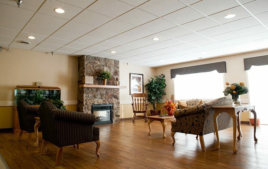 A cozy living room with sofas, a stone fireplace, and wooden flooring.