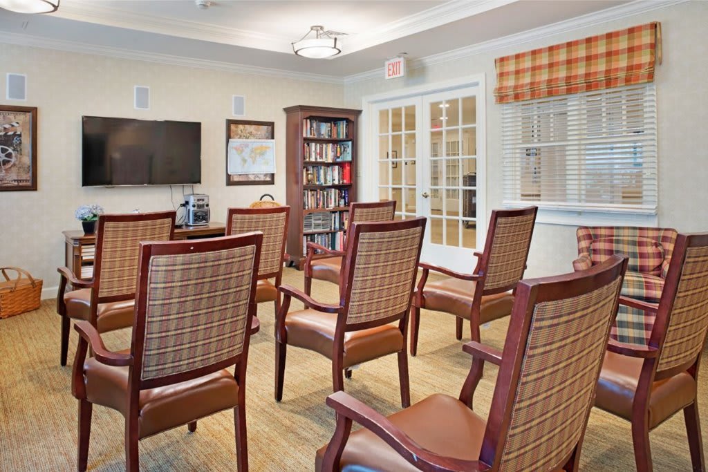 A cozy meeting room with arranged chairs, a bookshelf, and a television.