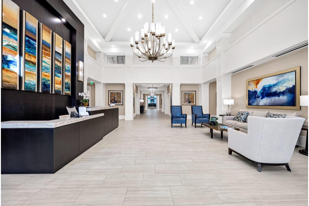 A spacious, elegantly designed lobby with a chandelier, reception desk, and comfortable seating area.