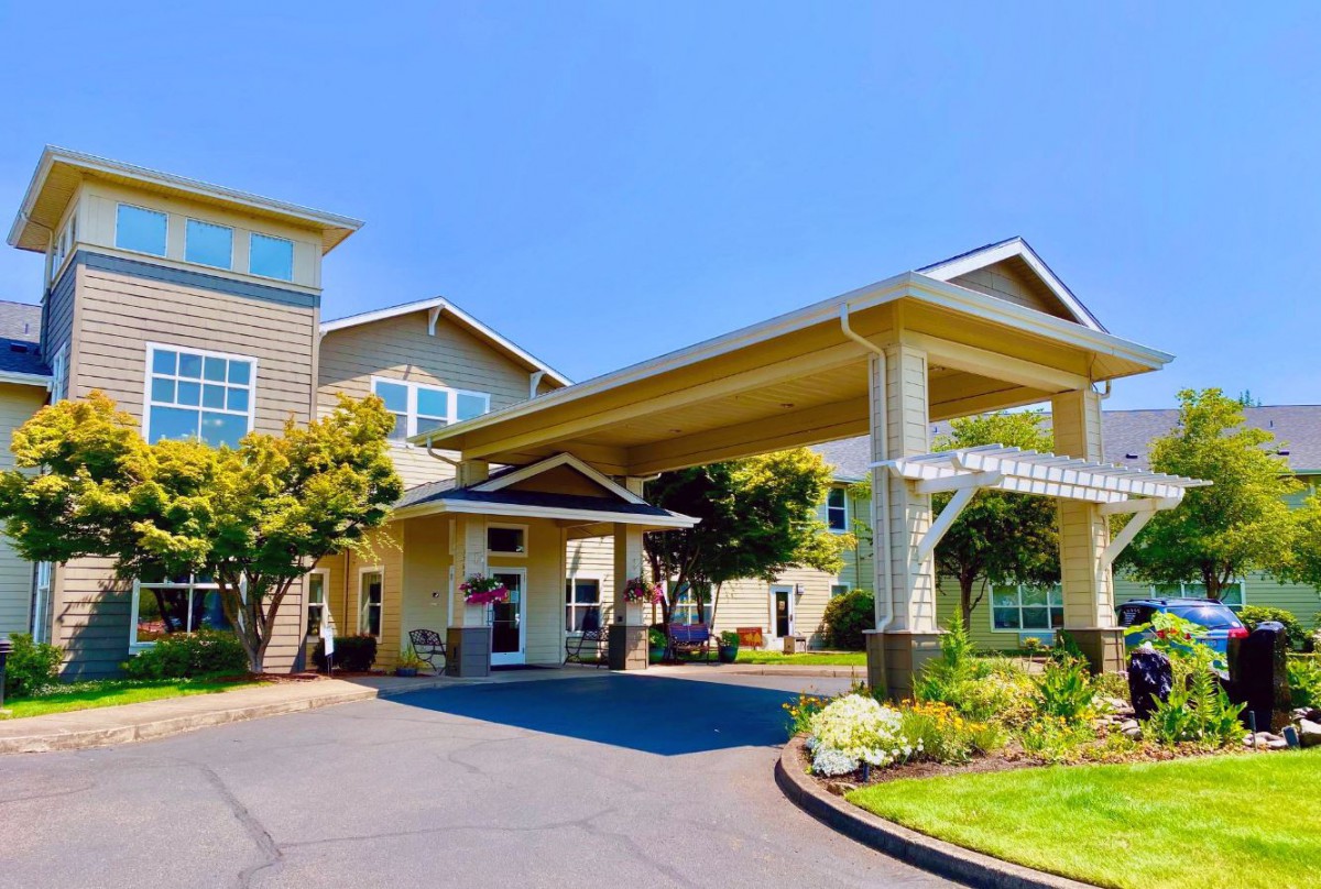 A modern building entrance with a covered driveway and landscaped surroundings.